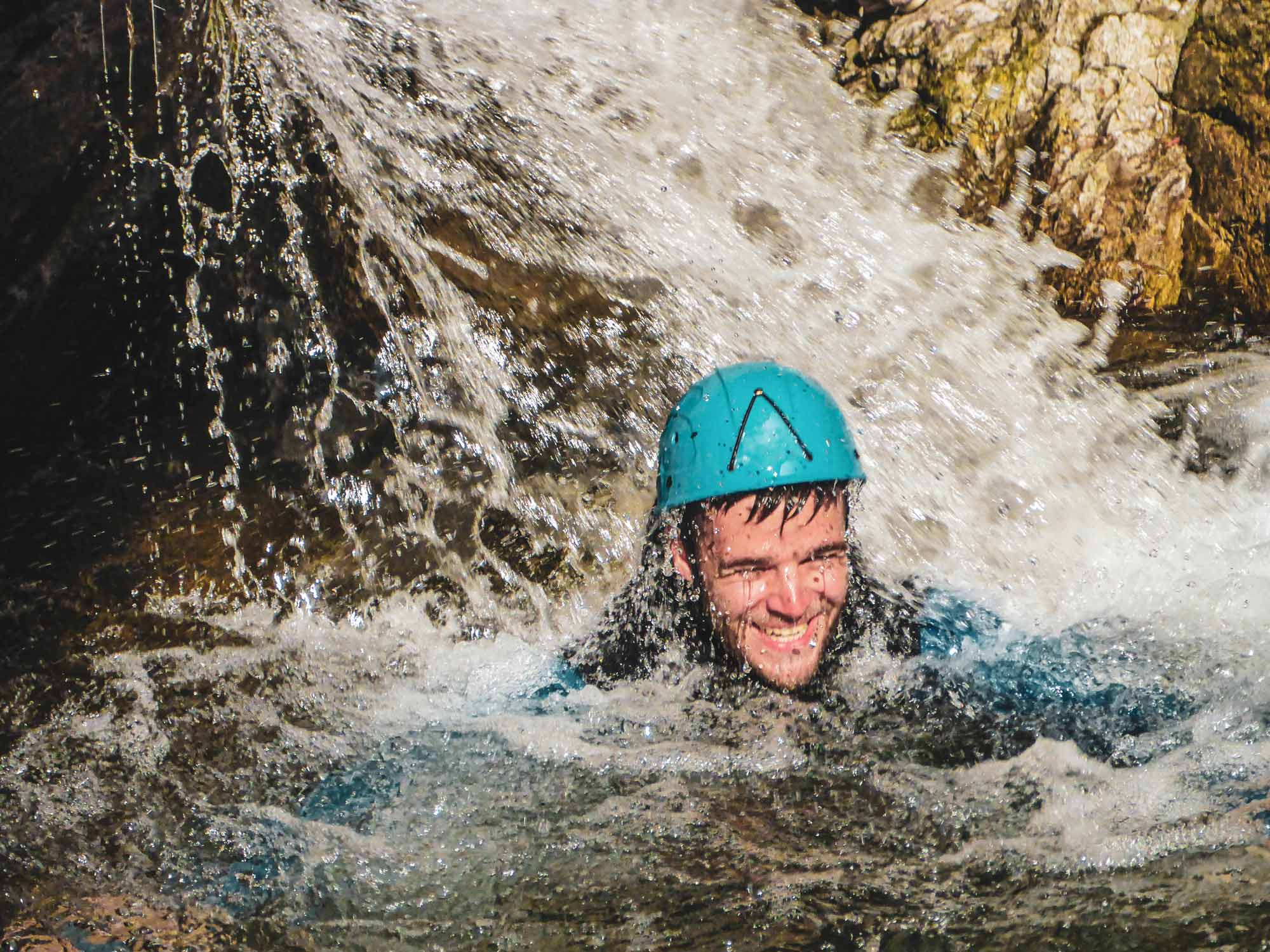 un pratiquant sous une cascade dans le canyon demi-journée Azéro avec Nature Canyon Ardèche