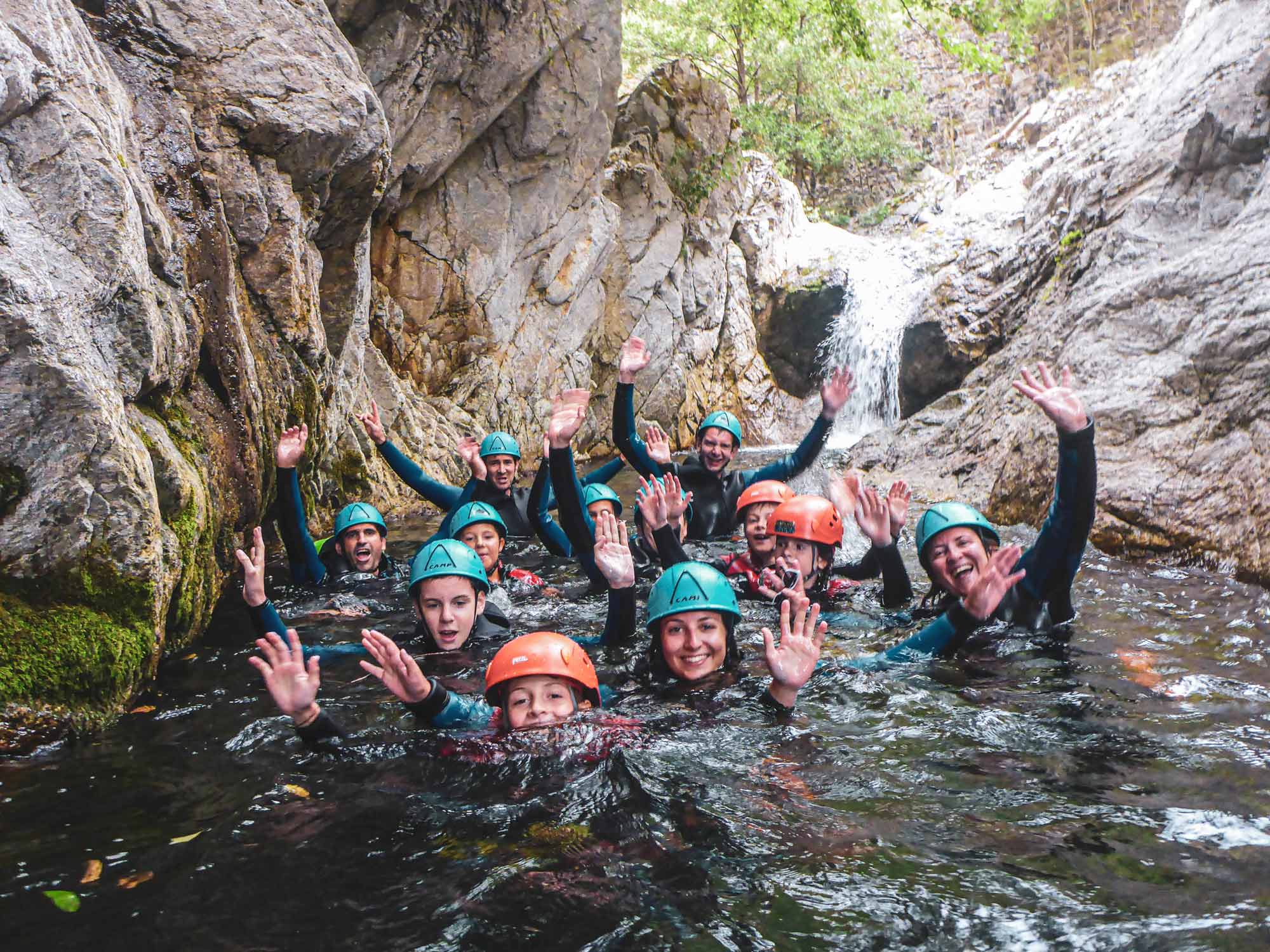 Un groupe avec des enfants dans la rivière au pied d'une cascade sur le parcours demi-journée Azéro avec Nature Canyon Ardèche