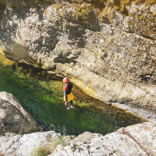 Enfant effectuant un saut dans une étroiture sur le parcours canyoning de l'Azéro avec Nature Canyon Ardèche